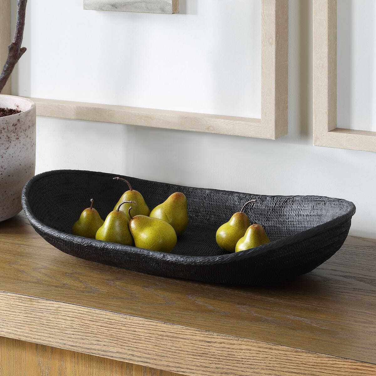 Black woven bowl with pears on a wooden surface