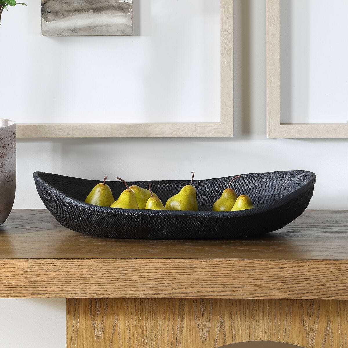Black woven bowl with pears on a wooden surface