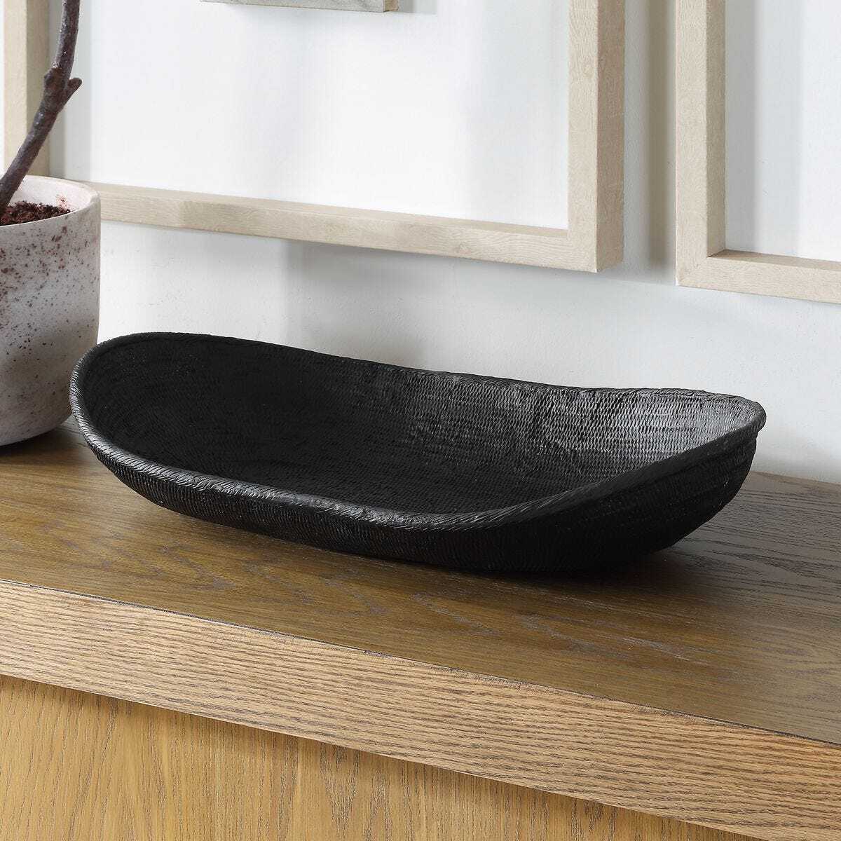 Black woven bowl on a wooden surface with a neutral background