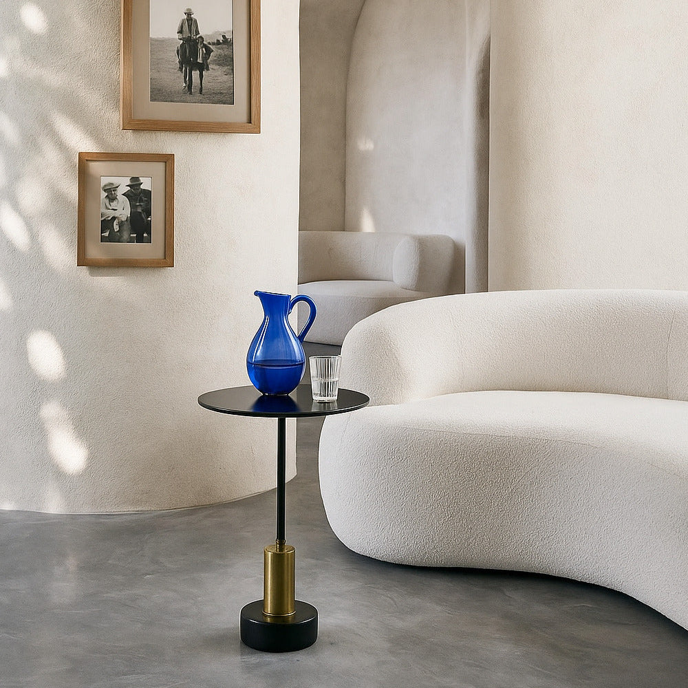 Modern interior with a blue vase on a small table, framed pictures on the wall, and a curved white sofa.