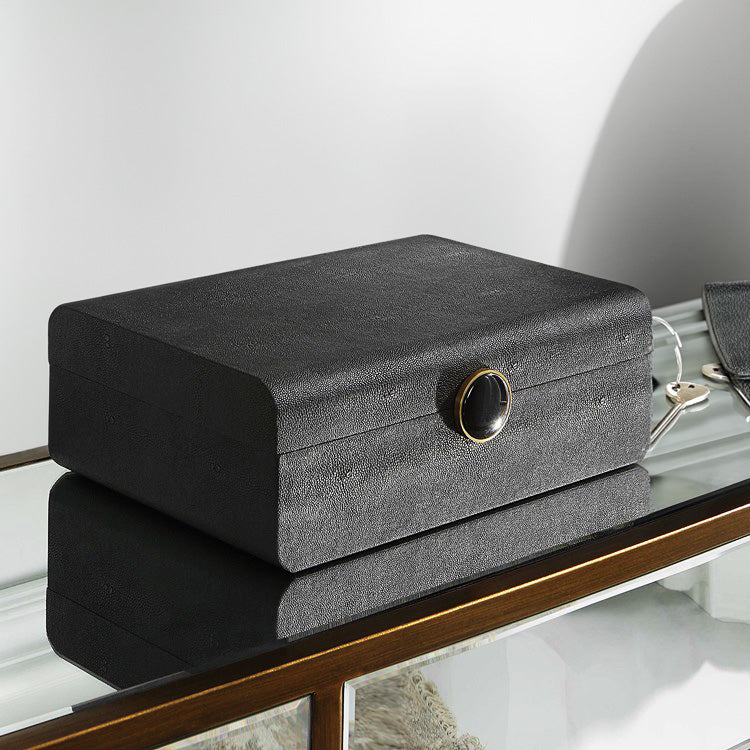 sleek black shagreen box on a mirrored console with wallet and keys