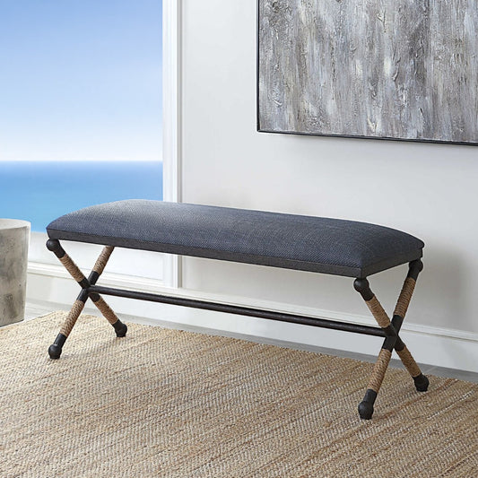 Blue bedroom bench with tan rug and ocean view and contemporary art above in living room.