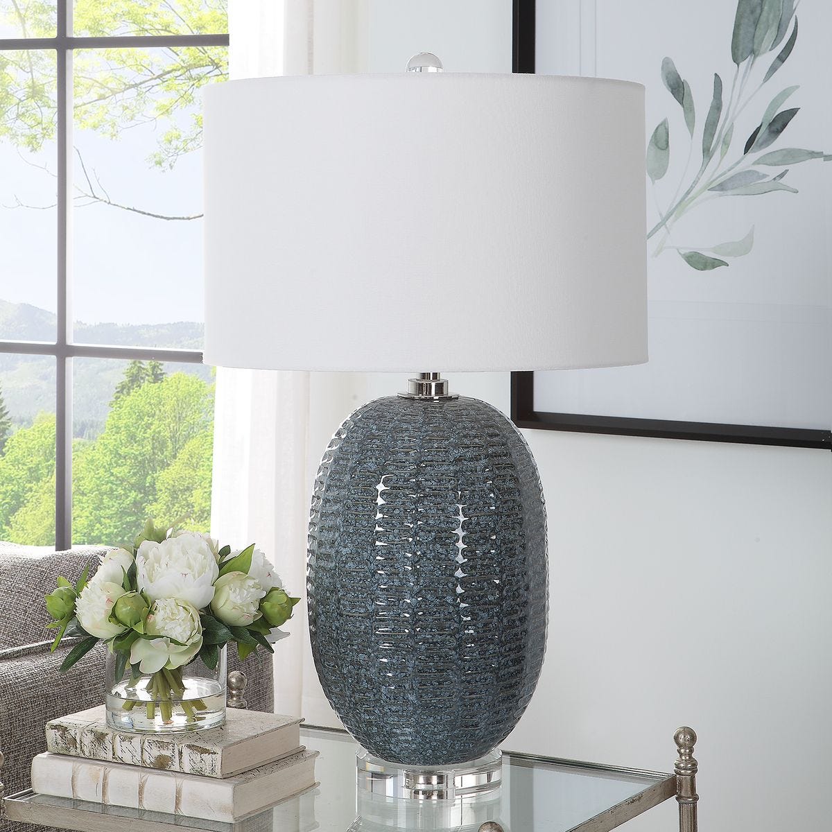 Decorative lamp with textured base on a table in a room with a window and plant.