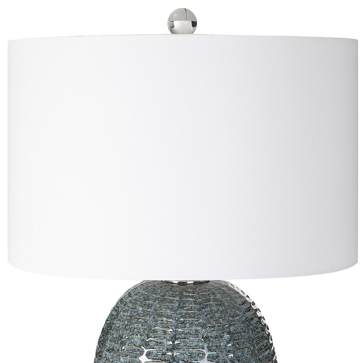 Table lamp with textured base and white shade on a white background