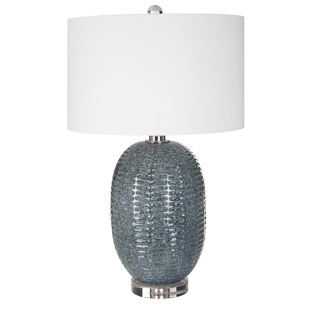 Table lamp with textured base and white shade on a white background