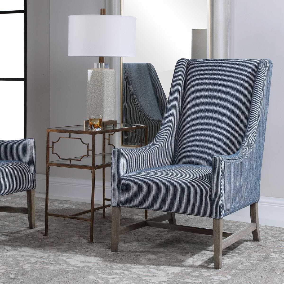 Blue striped armchair in a room with a side table and lamp.