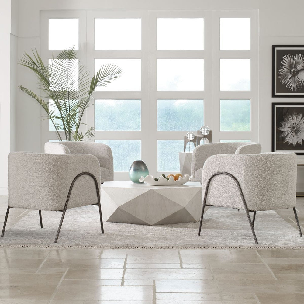 Modern living room with beige chairs, a coffee table, and large windows.