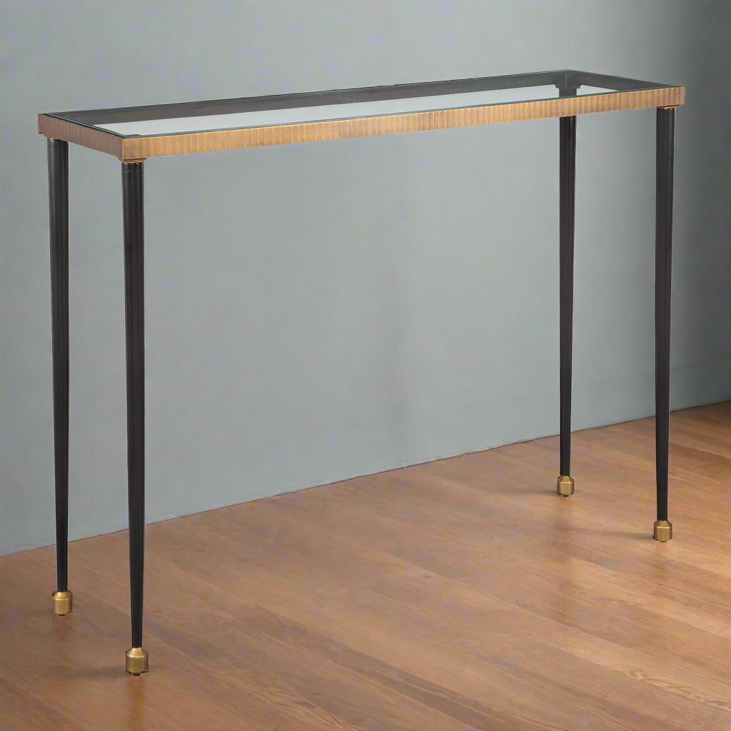 Brass console table with glass top in entryway.