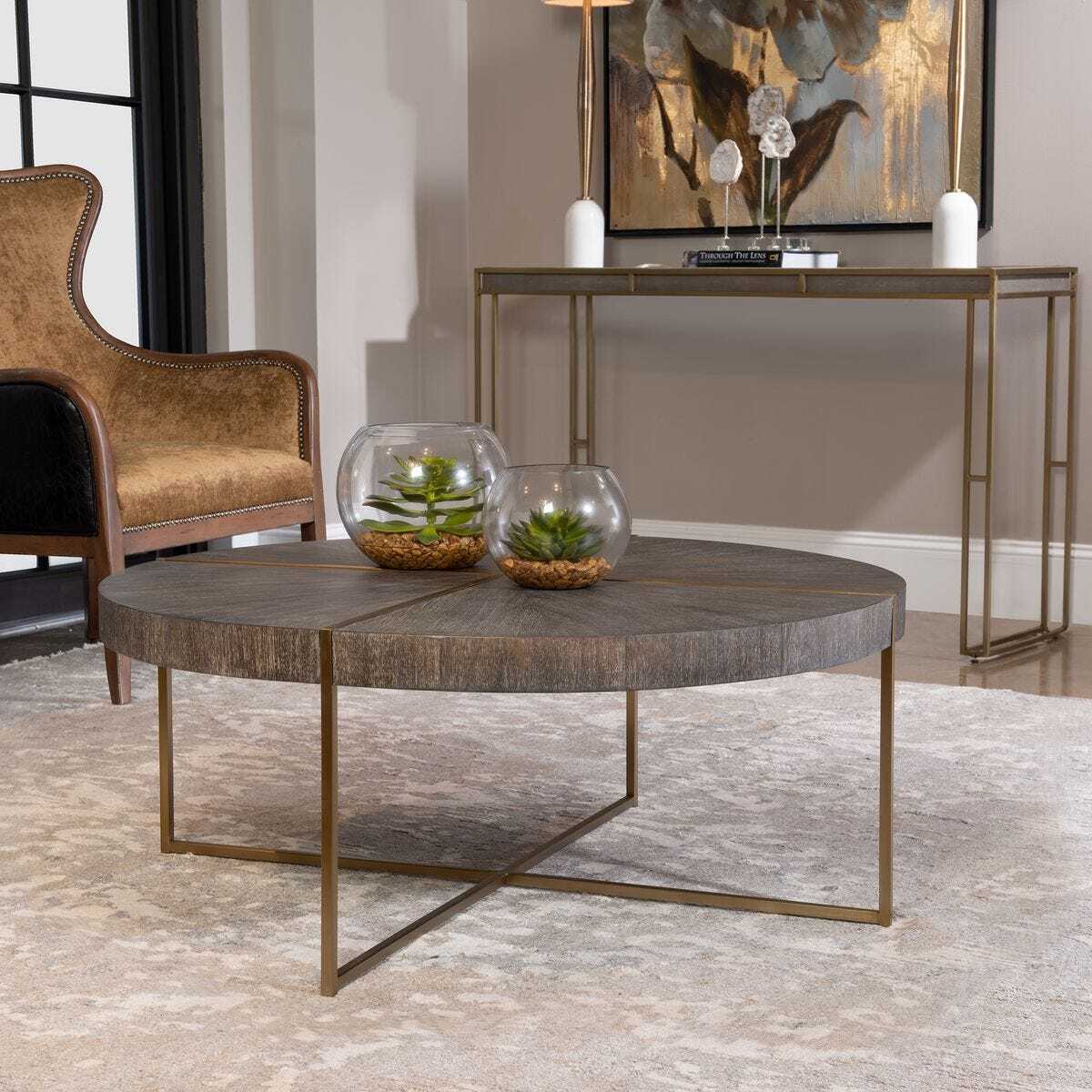 Round wooden coffee table with metal legs in a living room setting.