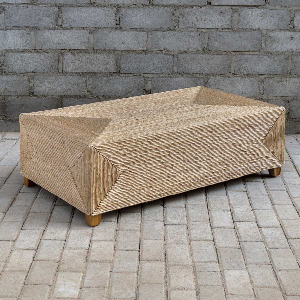 Woven outdoor coffee table on a brick patio with a brick wall background