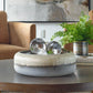 Textured ceramic bowl in neutral colors with decorative glass orbs inside on a coffee table.