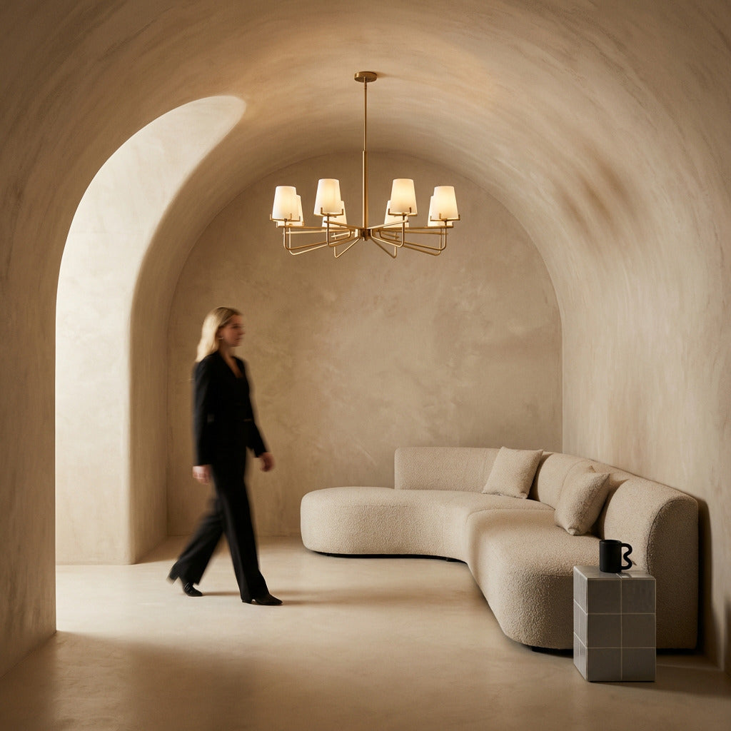 Modern interior with a woman walking past a curved sofa and chandelier.