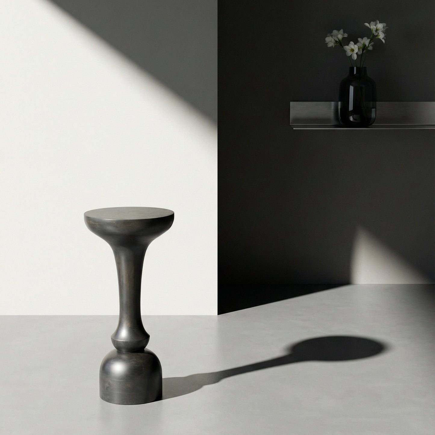 Dark gray stool on a light surface with a black wall and white flowers in the background