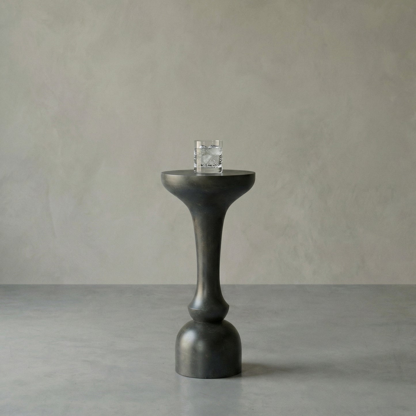 Black pedestal table with a glass on a gray background