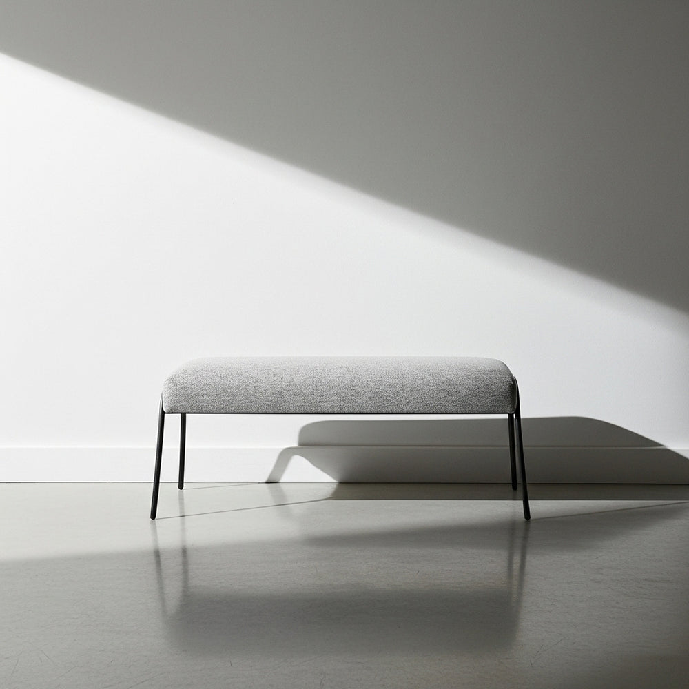 Gray bench against a white wall with soft shadows