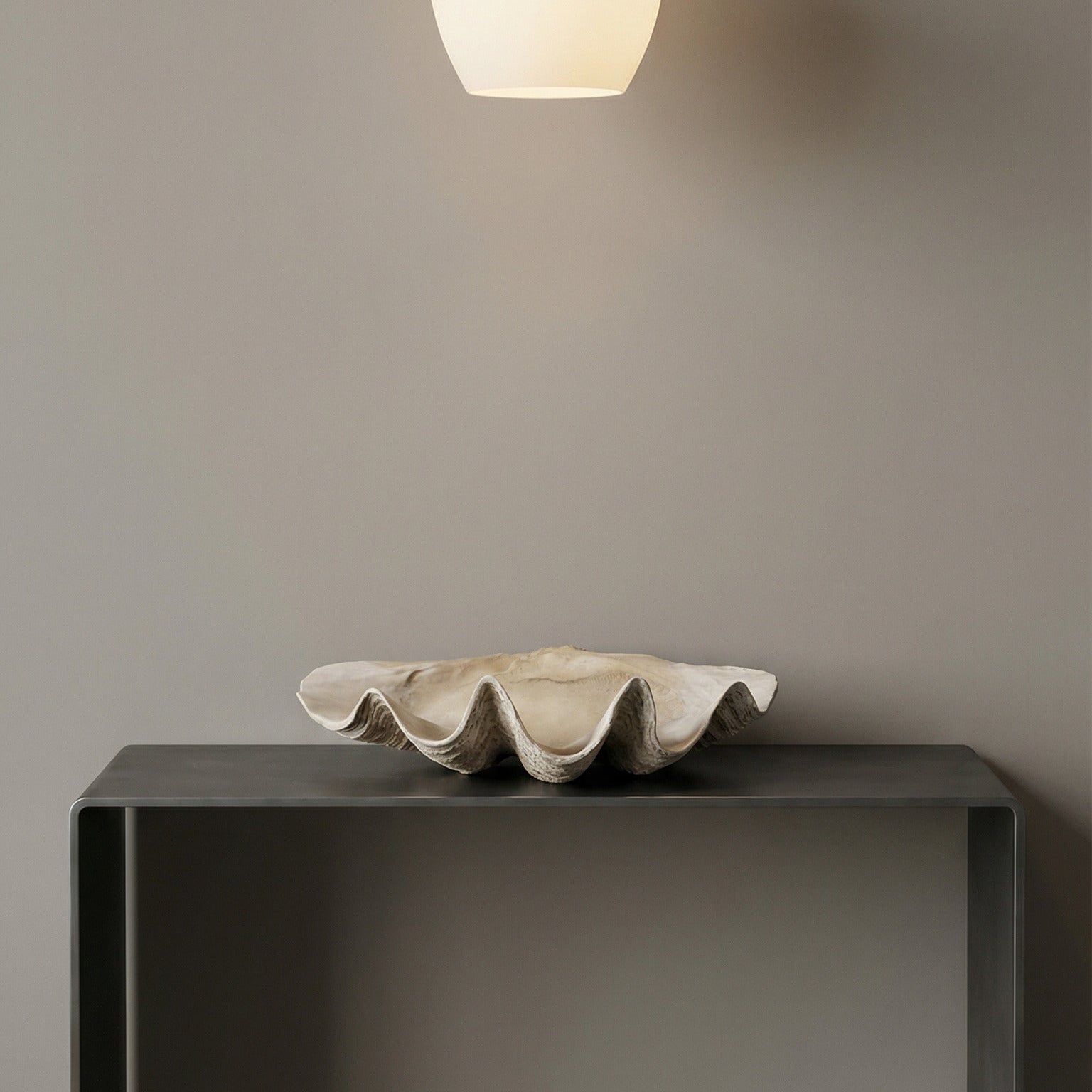 Pendant light fixture hanging above a dark surface with a neutral background