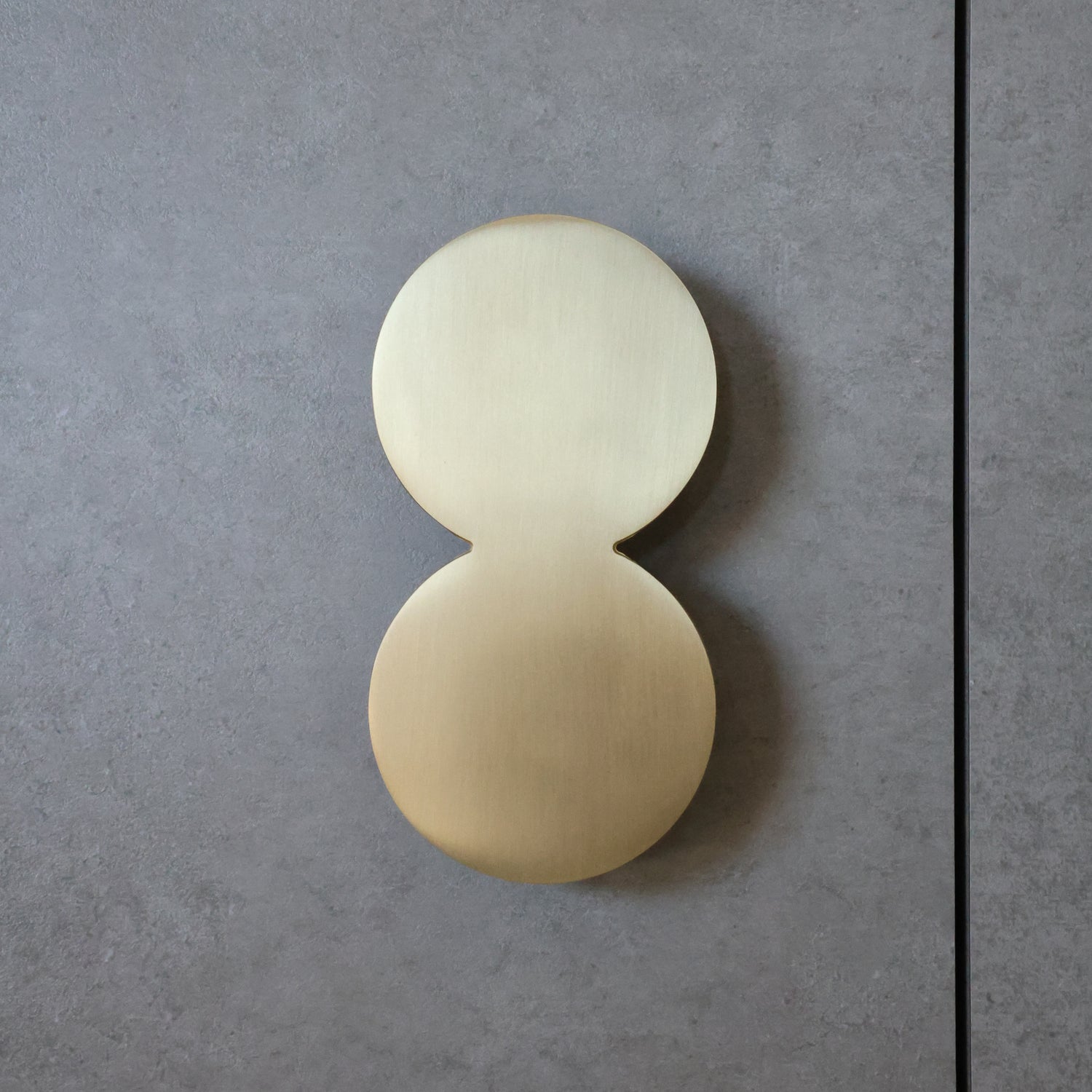 Modern cabinet pull on a gray concrete wall.