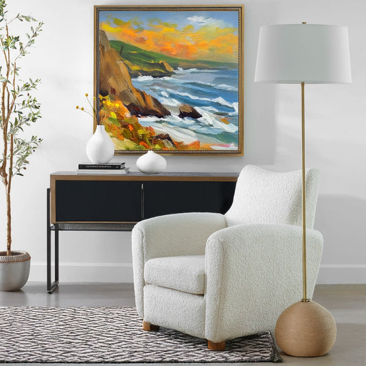 Rattan base floor lamp with white decorative chair and black console with coastal art.