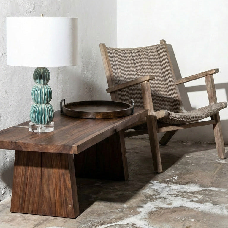 Wooden chair and table with a lamp against a white wall.