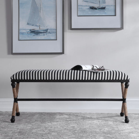 A bench with rustic iron is accented by a cushioned top, a sturdy sailor-striped cotton in crisp navy and cream.