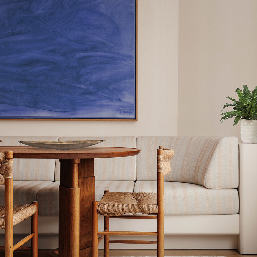 Coastal dining table with narrow tray made of antique brass and an ocean inspired piece of art.