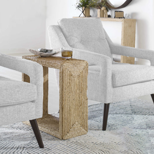 Woven narrow end table between two chairs with decorative bowl and glass of scotch.