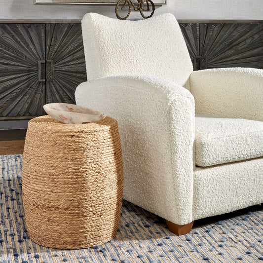 Round coastal end table with marble tray and black console and patterned blue rug.