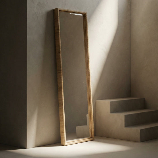 Long standing mirror leaning against a wall with light casting shadows