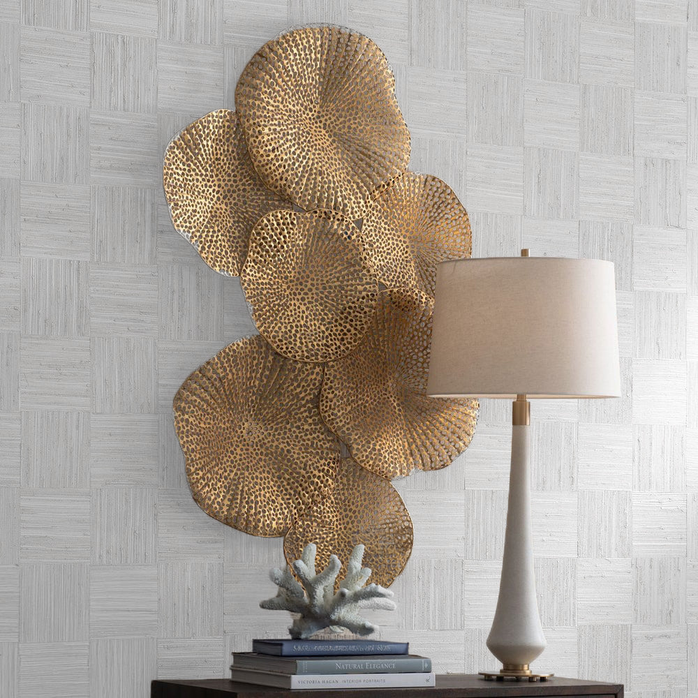 Brass coastal metal wall art above wood console, coastal table lamp, and decorative coral.