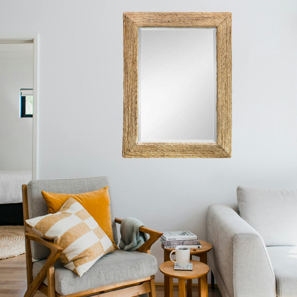 Woven coastal mirror hanging in living room above a sofa and couch with hardwood floors.