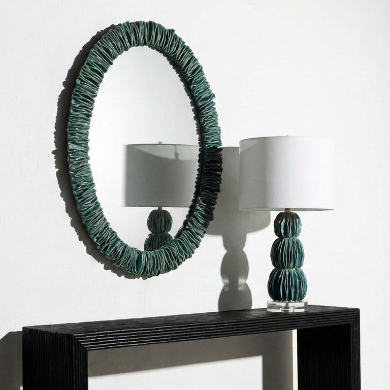 Modern console table with round mirror and decorative lamps on a white background