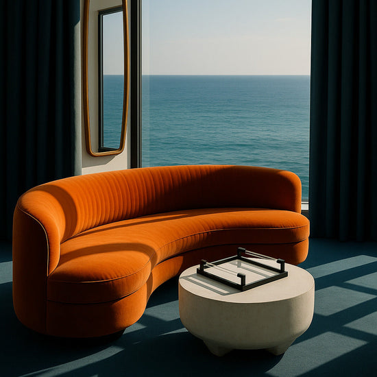 Orange curved sofa in a room with large windows overlooking the ocean.