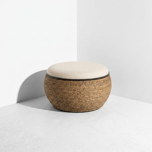 A round pouf ottoman with a textured brown woven base and a white cushioned top, set against a minimalist white background.
