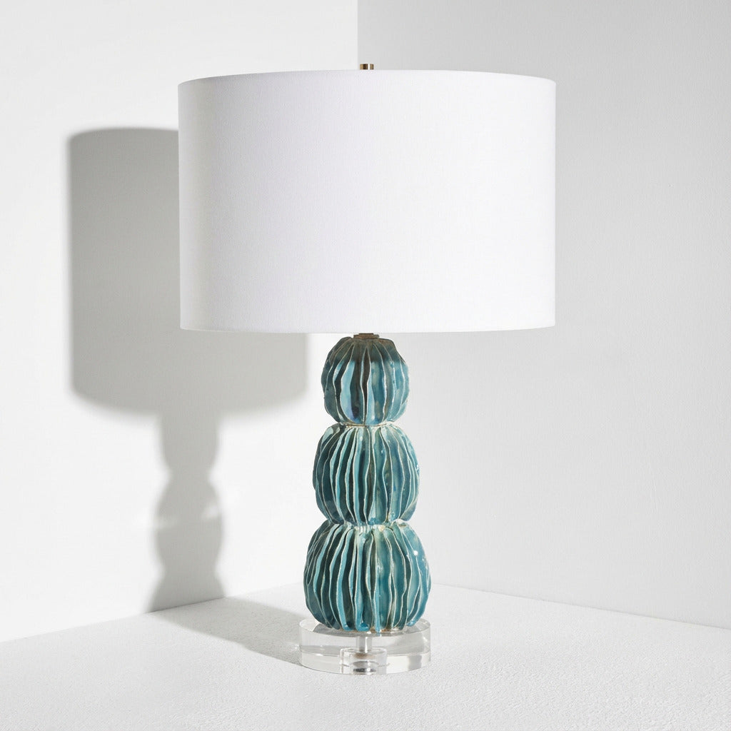 Table lamp with a textured blue base and white shade on a light gray background