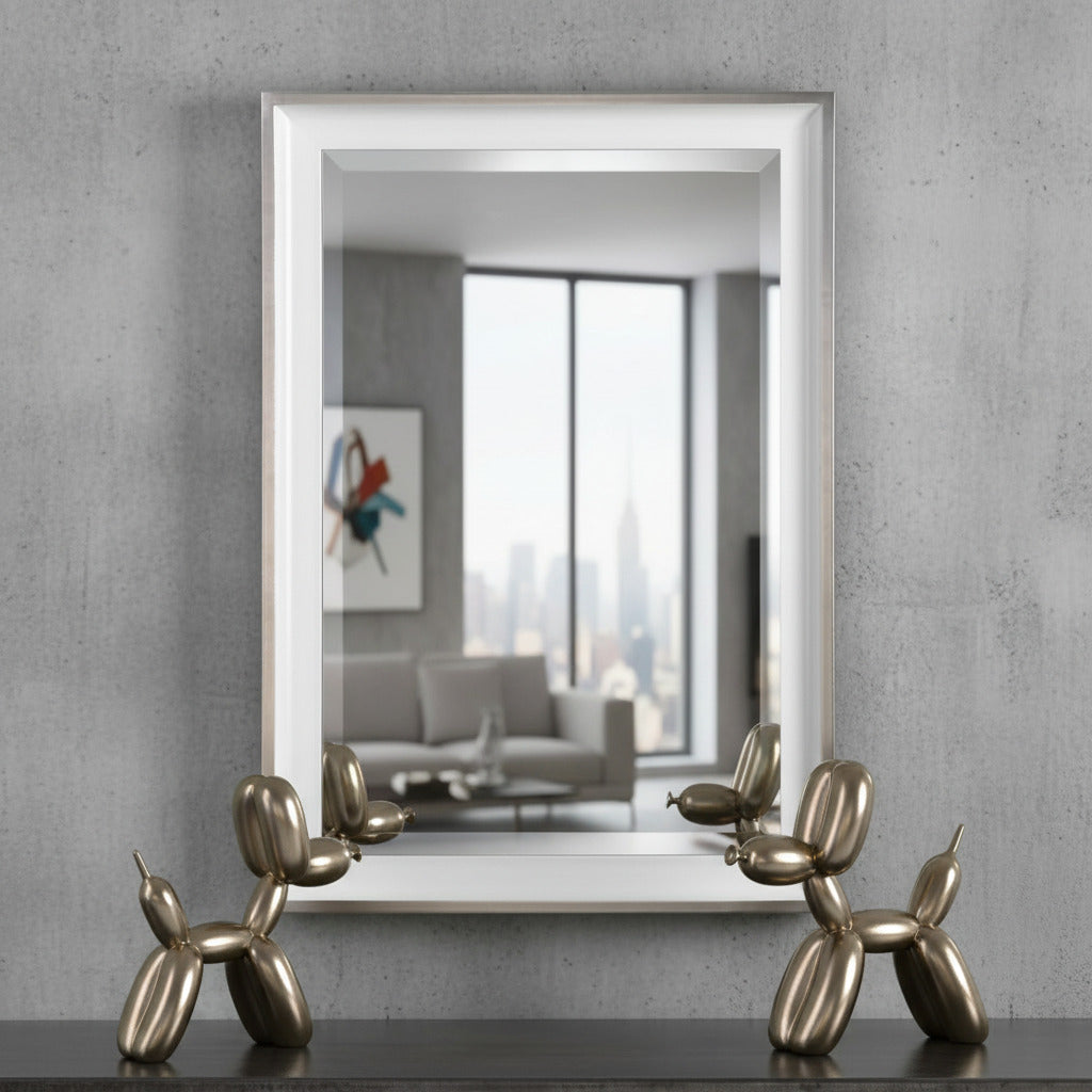 Bronze dog sculpture in front of a large mirror on a gray wall.