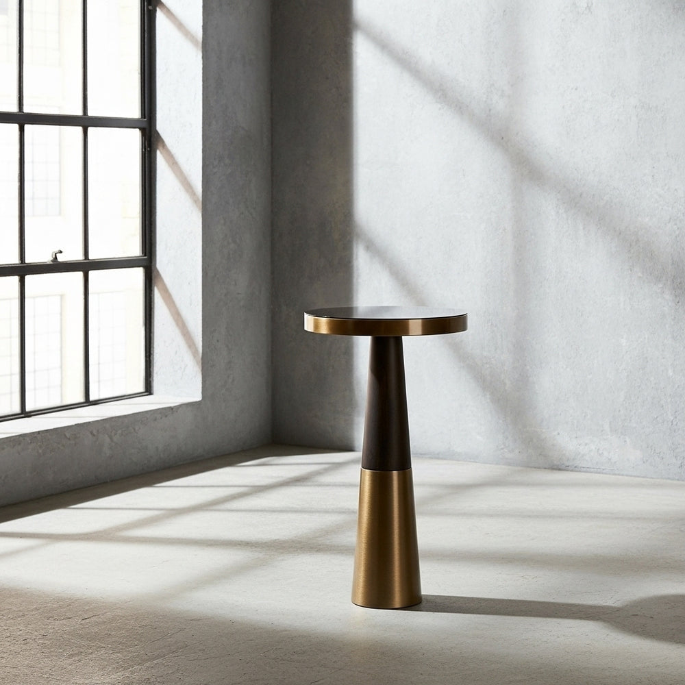 Bronze side table in a room with large windows and concrete walls.