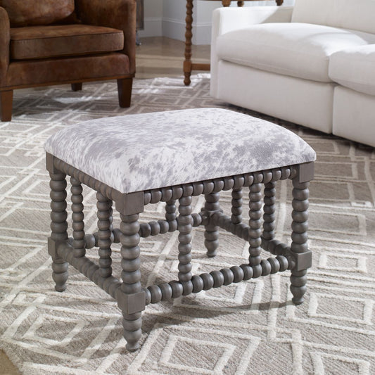 Cowhide ottoman in living room with white and gray colors.