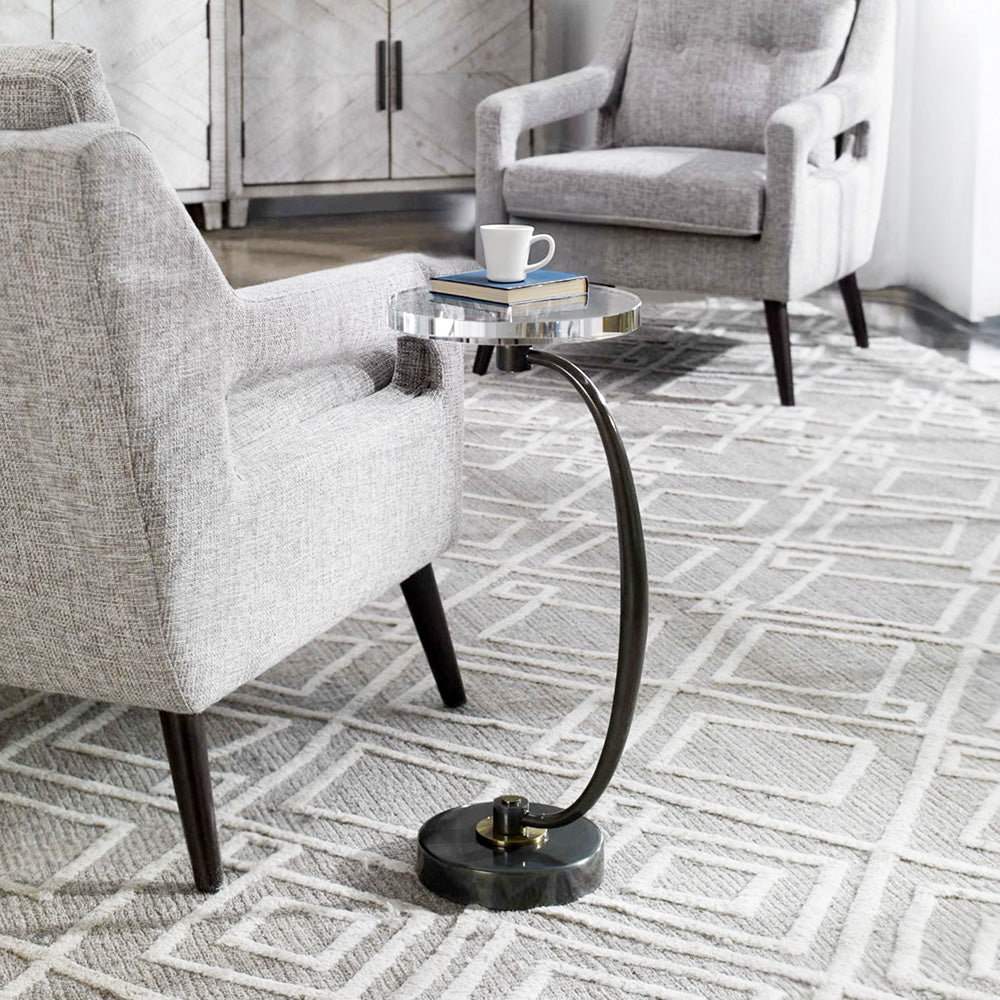 Curved metal accent table with a drink of scotch on top in a living room.