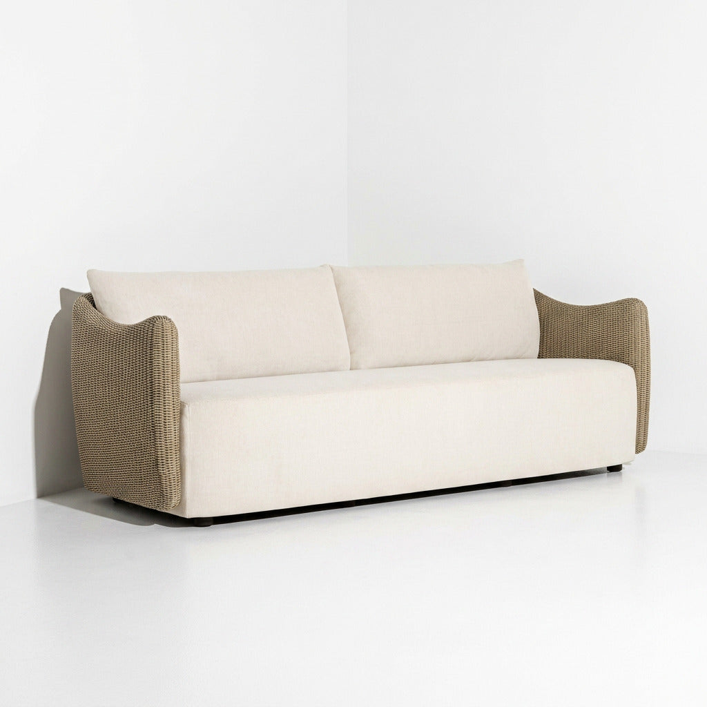 A modern two-seater sofa with cream-colored fabric cushions and textured brown woven armrests, shown in a minimalist studio setting.