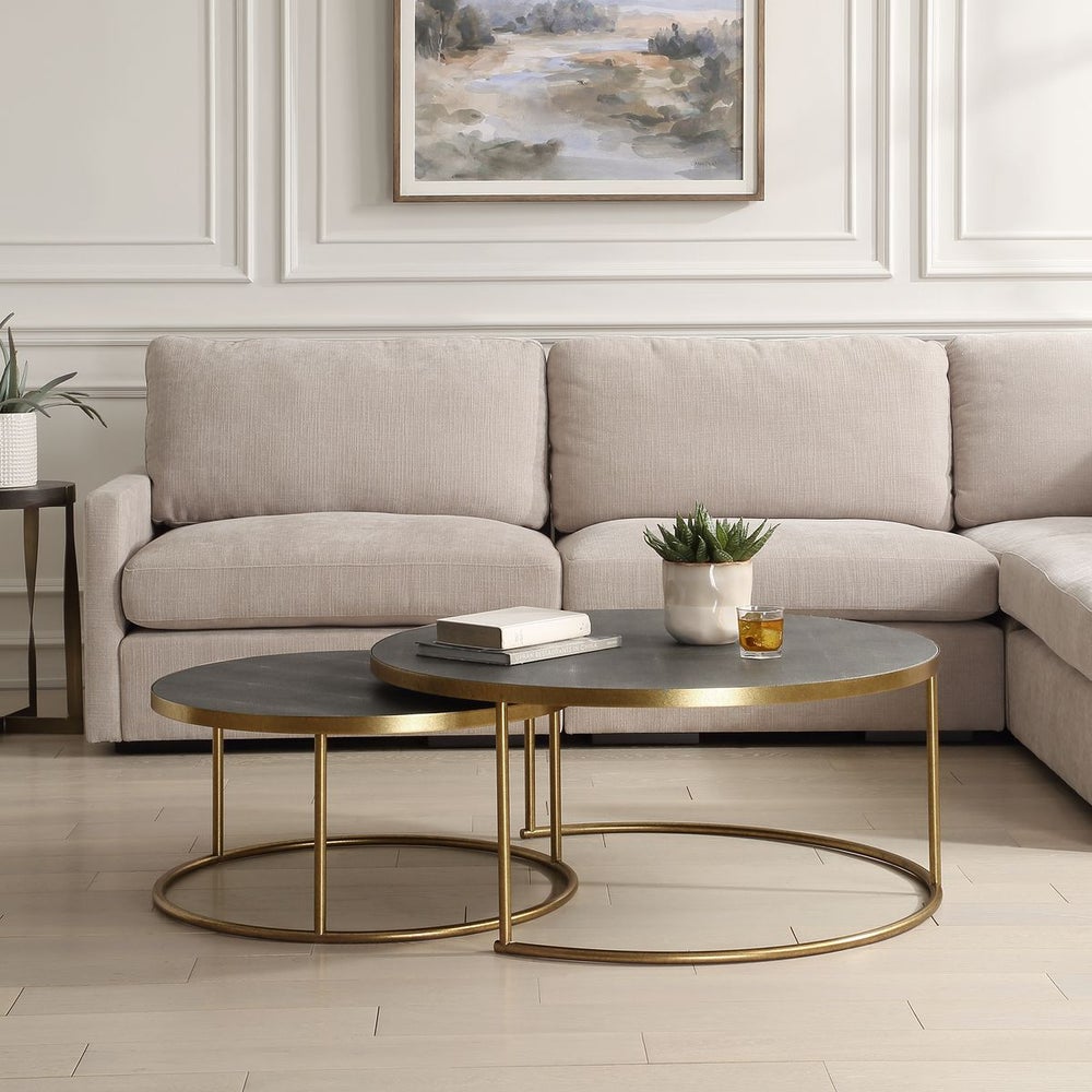 Set of two dark gray shagreen and brass nesting coffee tables in a modern living room.