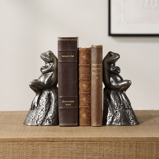 Two metallic frog bookends on a white background