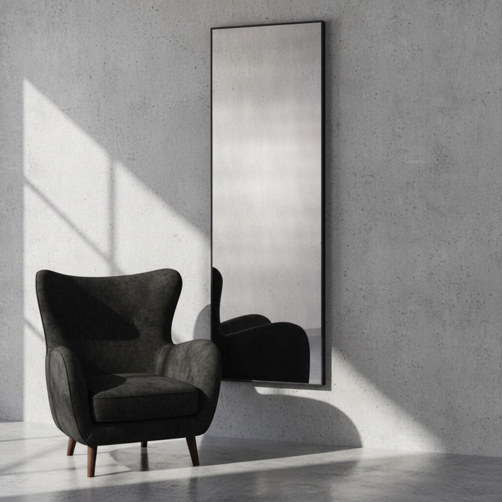 Dark gray armchair in a room with a large mirror on the wall.