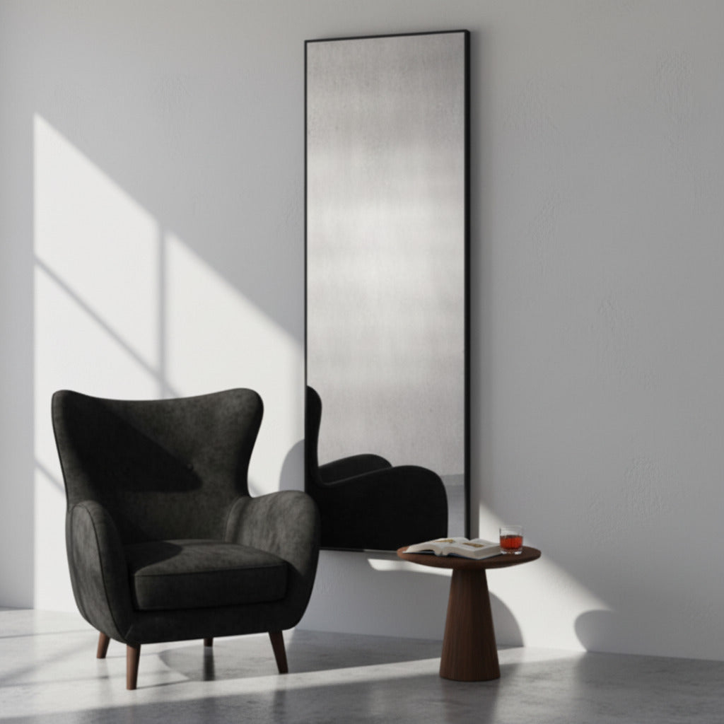 Modern black armchair in a minimalistic room with a tall mirror.