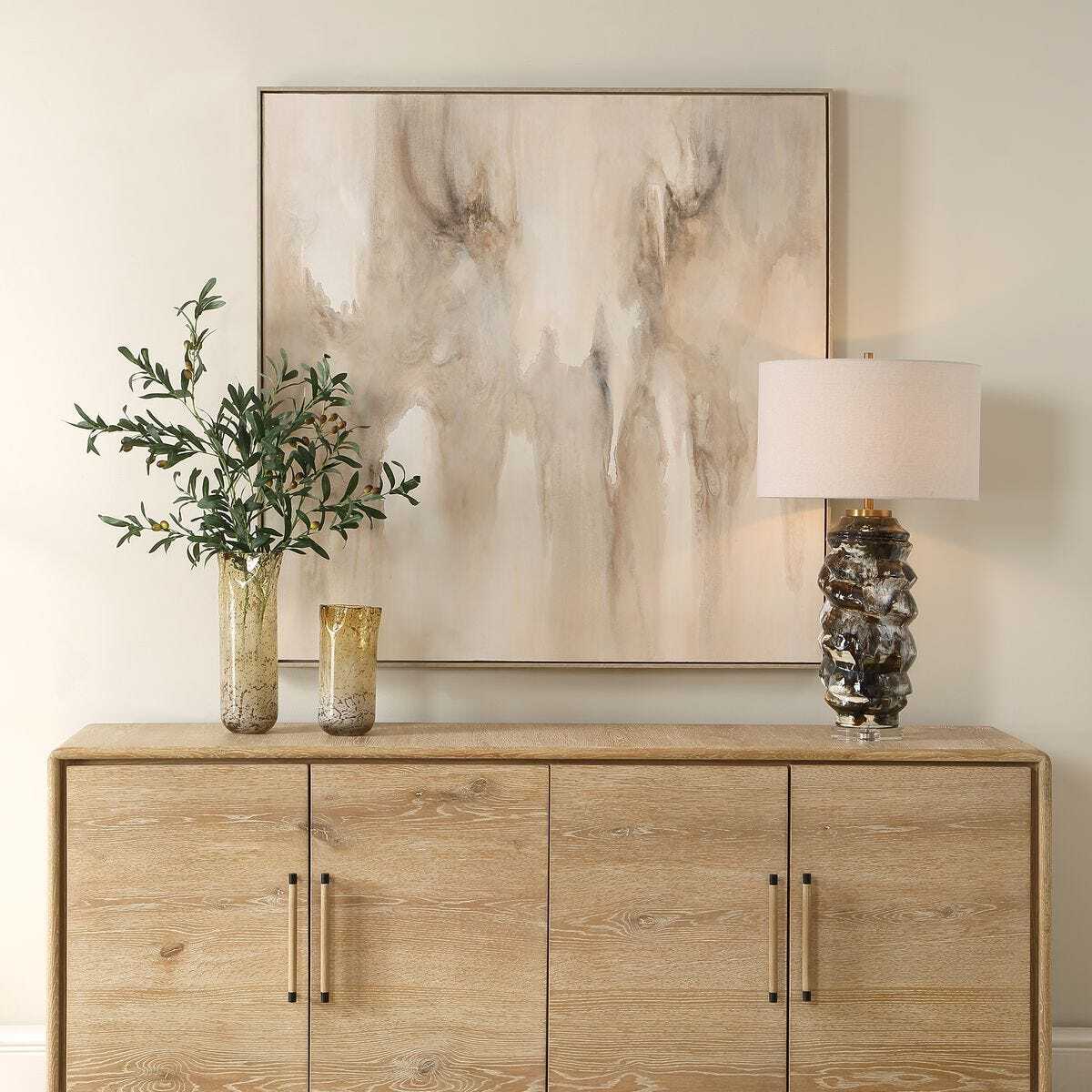 Wooden cabinet with decorative items including a vase, lamp, and abstract painting.
