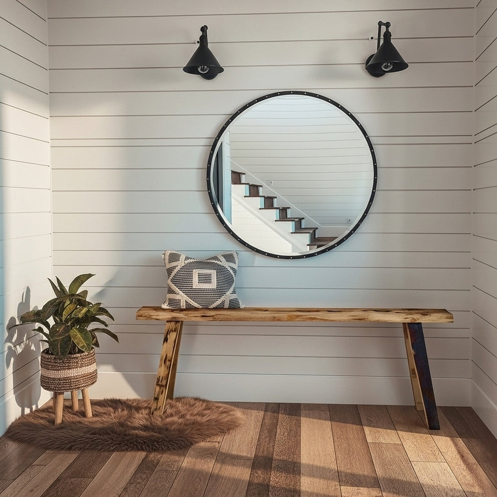 Foyer with round mirror, wooden bench, and decorative pillow on a light wood floor.