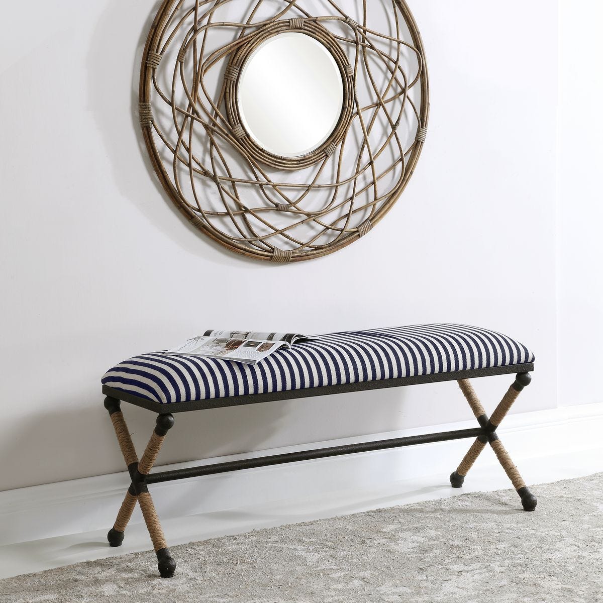 Striped bench with woven legs in front of a decorative wall mirror.