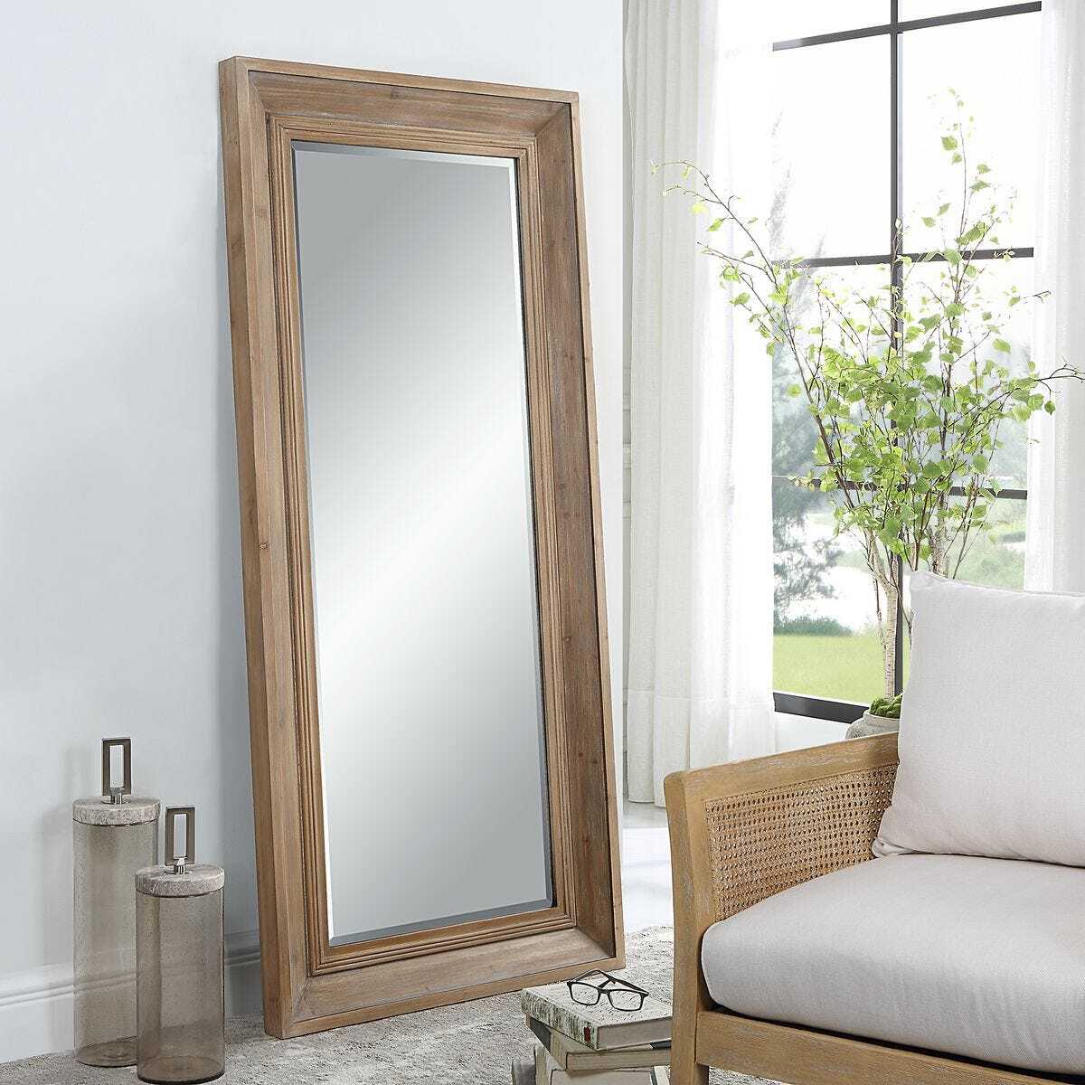 Wooden floor mirror in a room with a couch and decorative items.