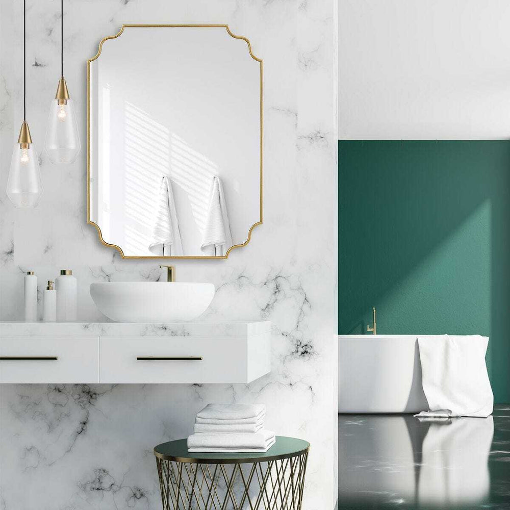 Modern bathroom with marble walls, gold-framed mirror, and white fixtures.