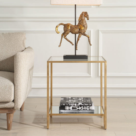 Gold-framed side table with two glass shelves on a white background