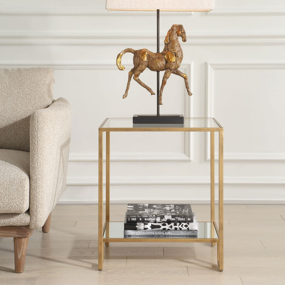 Glass, antique gold end table with gold frame and horse lamp in a living room setting